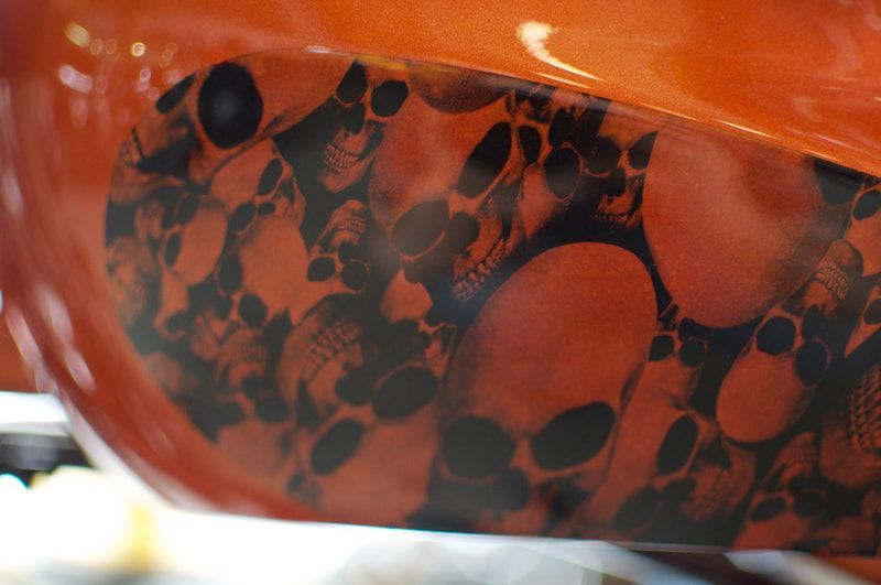 A close up of a motorcycle tank with skulls painted on it.
