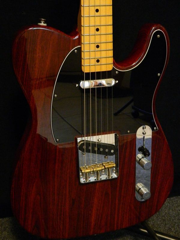 A red electric guitar is sitting on a stand