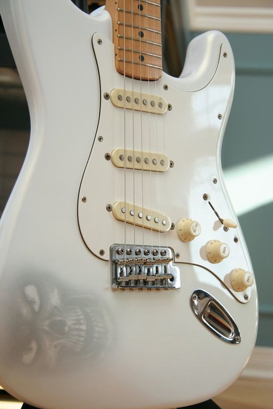 A white electric guitar with a skull on it