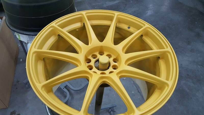 A yellow wheel is sitting on top of a black barrel.