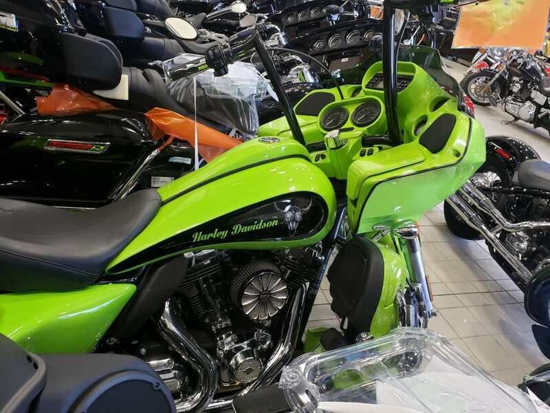 A green harley davidson motorcycle is parked in a showroom