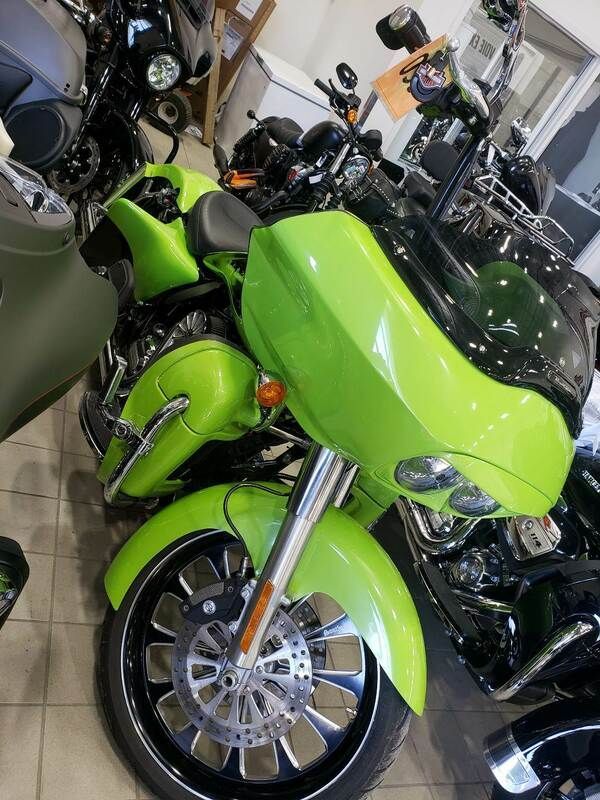 A green harley davidson motorcycle is parked in a showroom