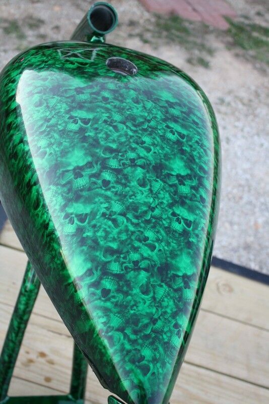 A green motorcycle tank is sitting on a wooden table.