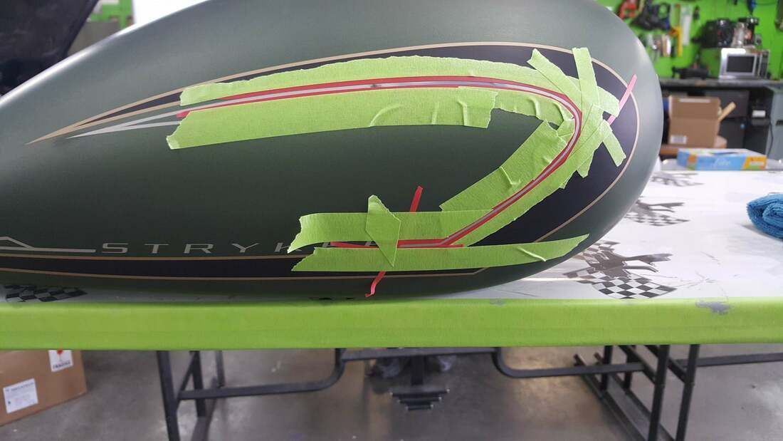 A motorcycle tank is sitting on top of a green table.