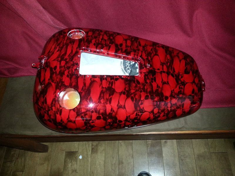 A red motorcycle tank is sitting on a wooden table