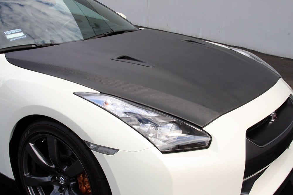 A white sports car with a carbon fiber hood
