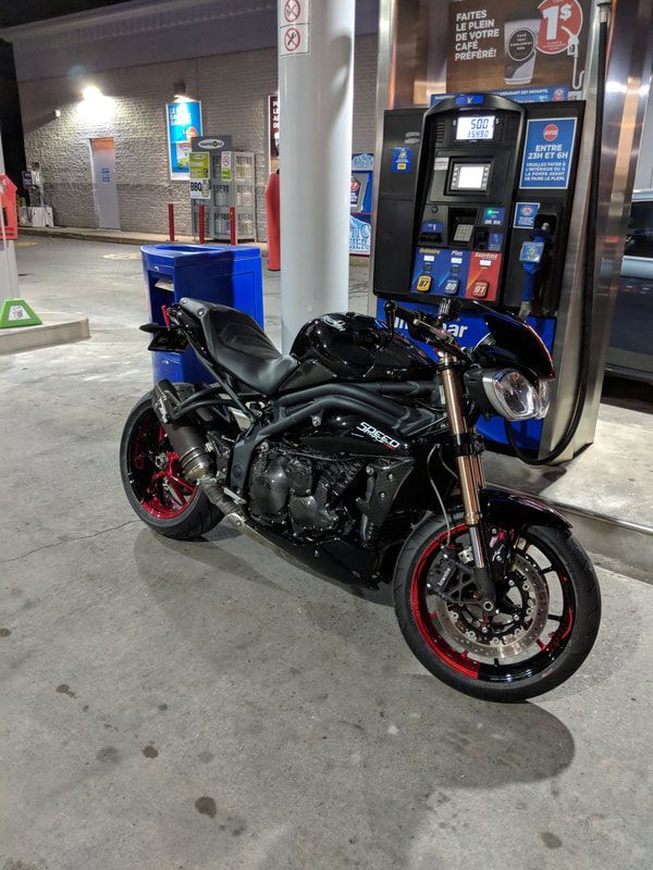 A motorcycle is parked in front of a gas pump at a gas station.