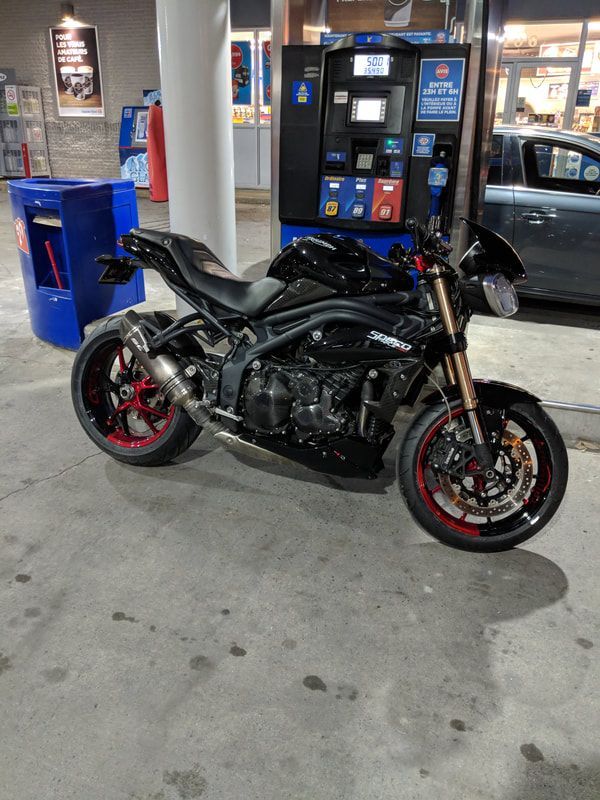 A motorcycle is parked in front of a gas pump at a gas station.