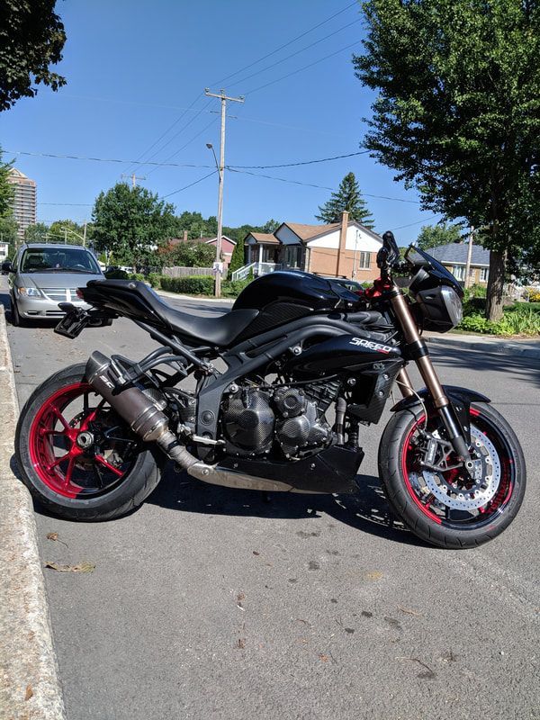 A black motorcycle with red wheels is parked on the side of the road
