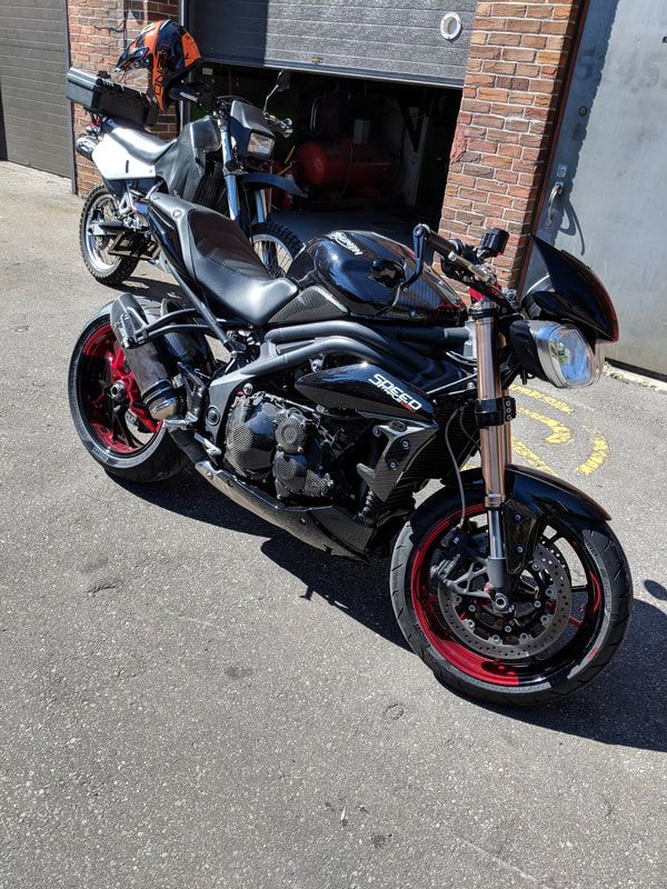 A black motorcycle is parked in front of a brick building.