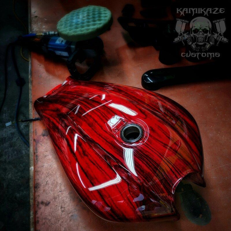 A red motorcycle tank is sitting on a wooden table