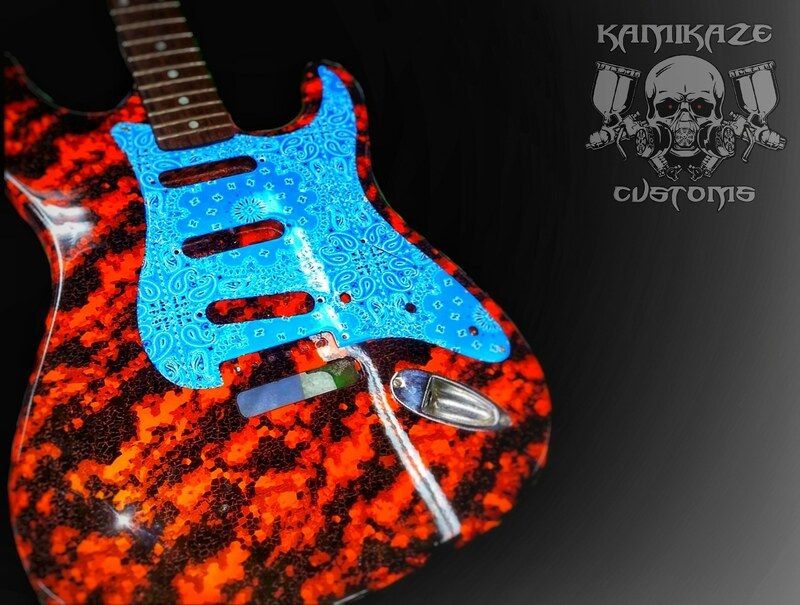 A red and blue electric guitar with kamikaze customs written on the bottom