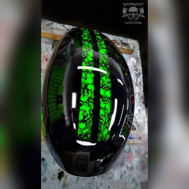A black helmet with green skulls on it is sitting on a table.