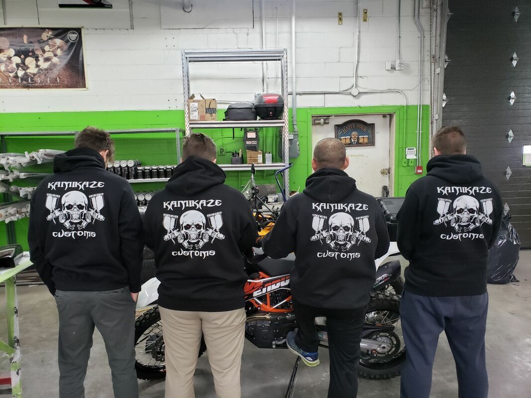 A group of men wearing black hoodies with skulls on the back