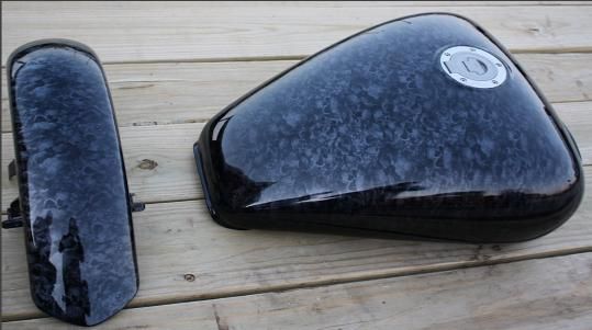 A black motorcycle tank is sitting on a wooden table