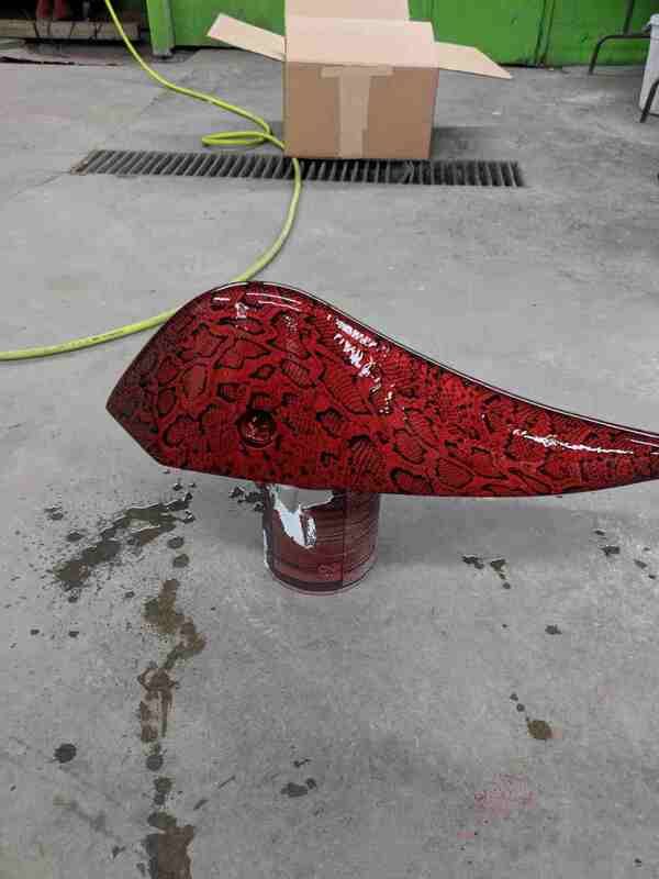 A red tank is sitting on a concrete floor next to a cardboard box.