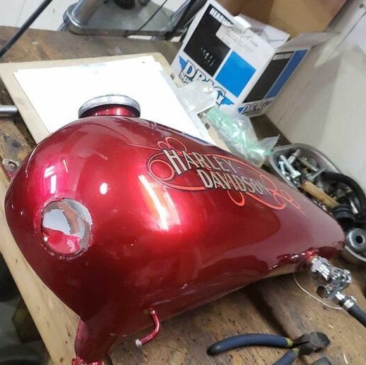 A red harley davidson motorcycle tank sits on a wooden table