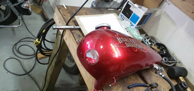 A red motorcycle tank is sitting on a wooden table.