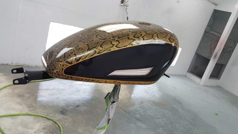 A motorcycle tank with a snake print is sitting on a table in a room.