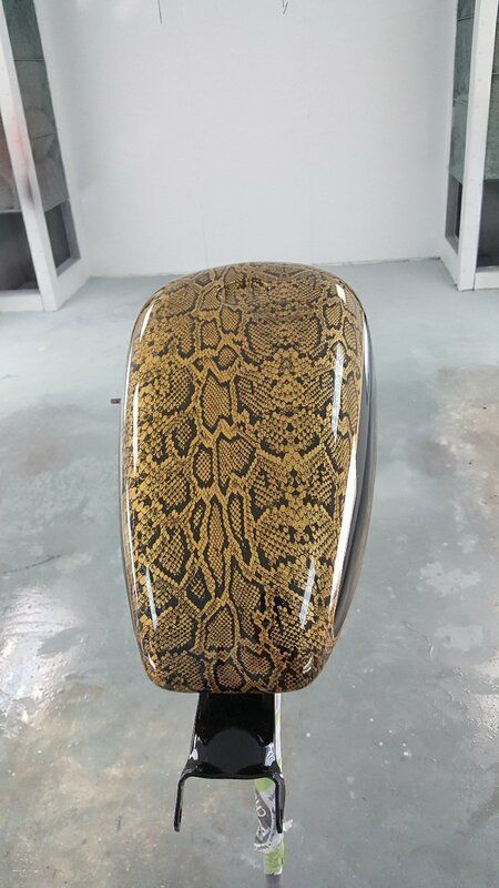 A motorcycle tank with a snake print painted on it.