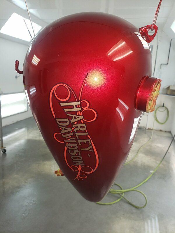 A red harley davidson motorcycle tank is hanging from the ceiling