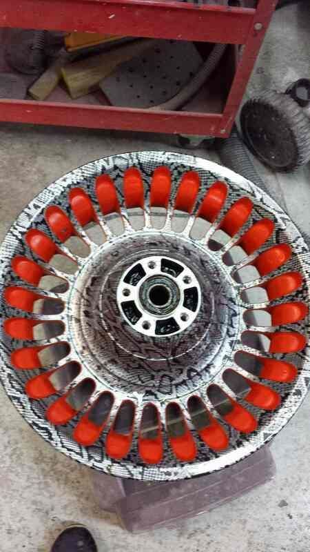 A close up of a wheel with red nuts on it.