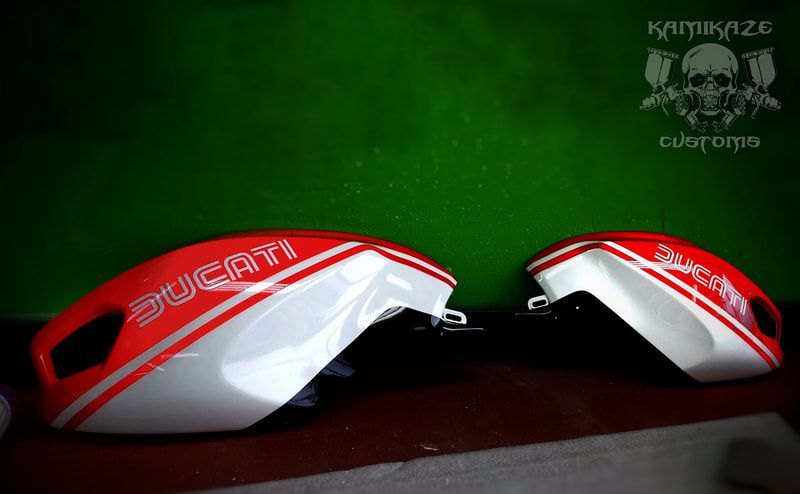 Two red and white ducati motorcycle tanks on a green background