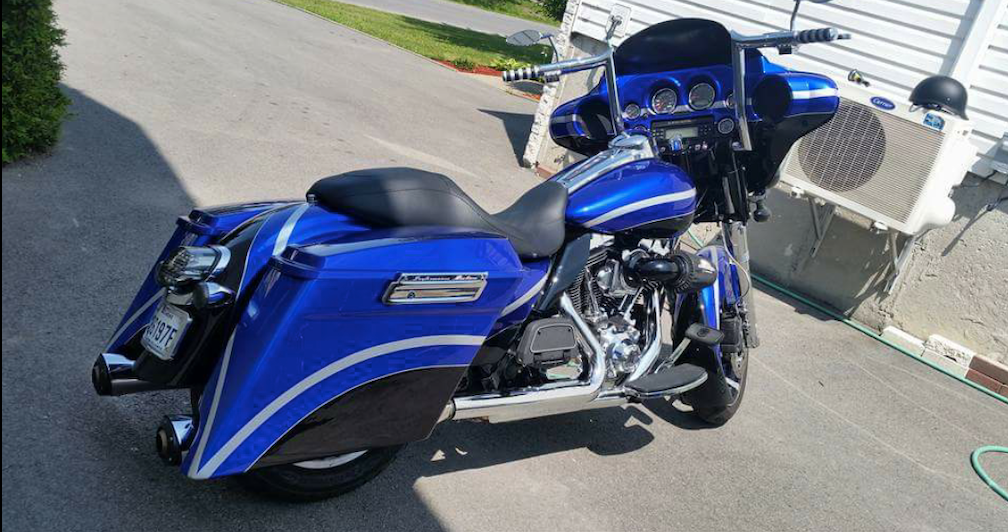 A blue harley davidson motorcycle is parked on the side of the road.