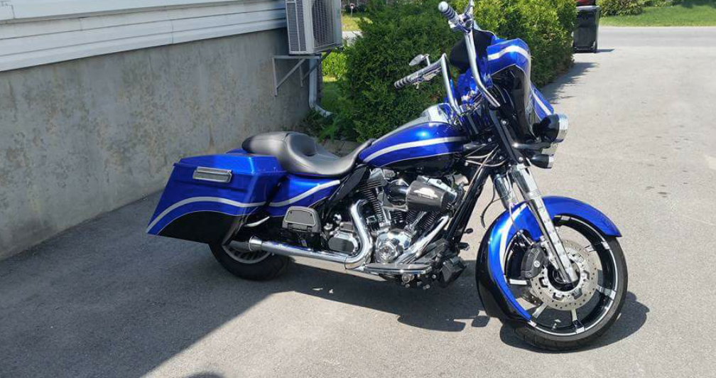 A blue harley davidson motorcycle is parked on the side of the road.