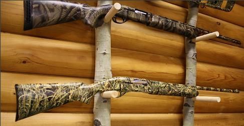 Two shotguns are hanging on a wooden wall.
