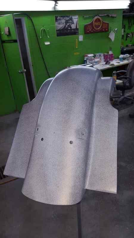 A motorcycle fender is sitting on the floor in a garage.