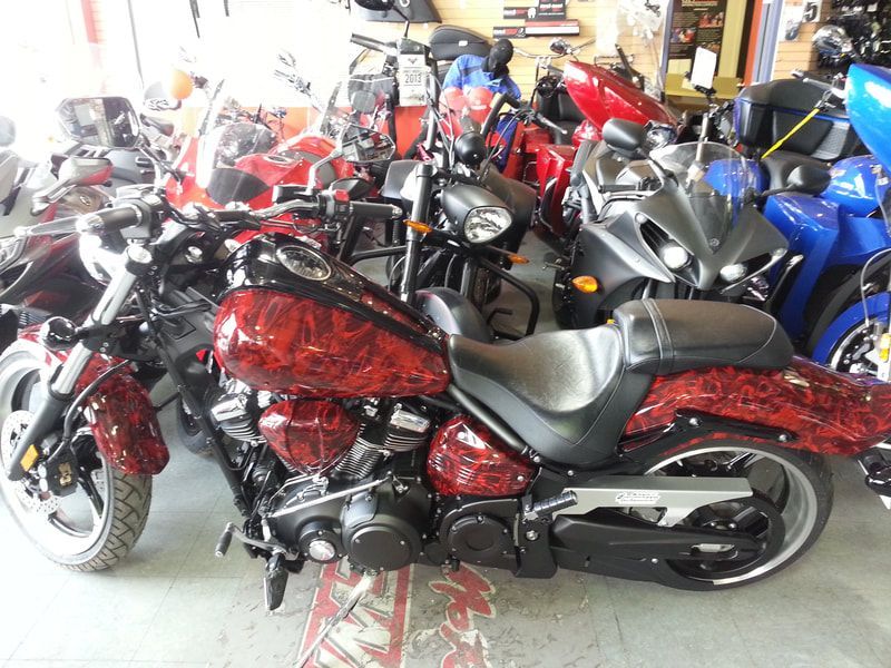 A red and black motorcycle is parked in a garage