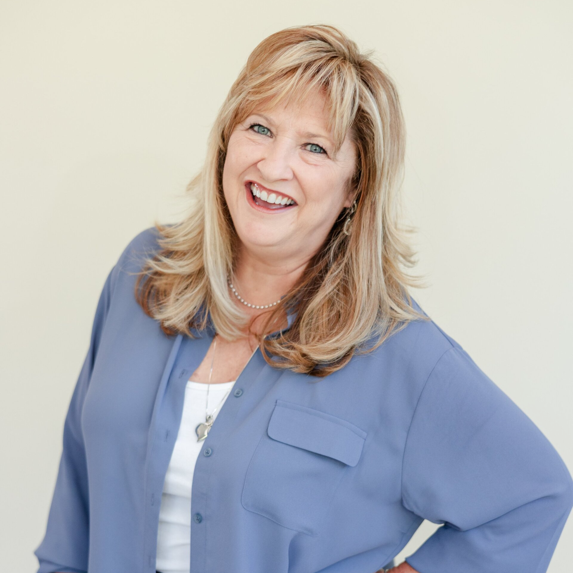 A woman in a blue shirt is smiling for the camera