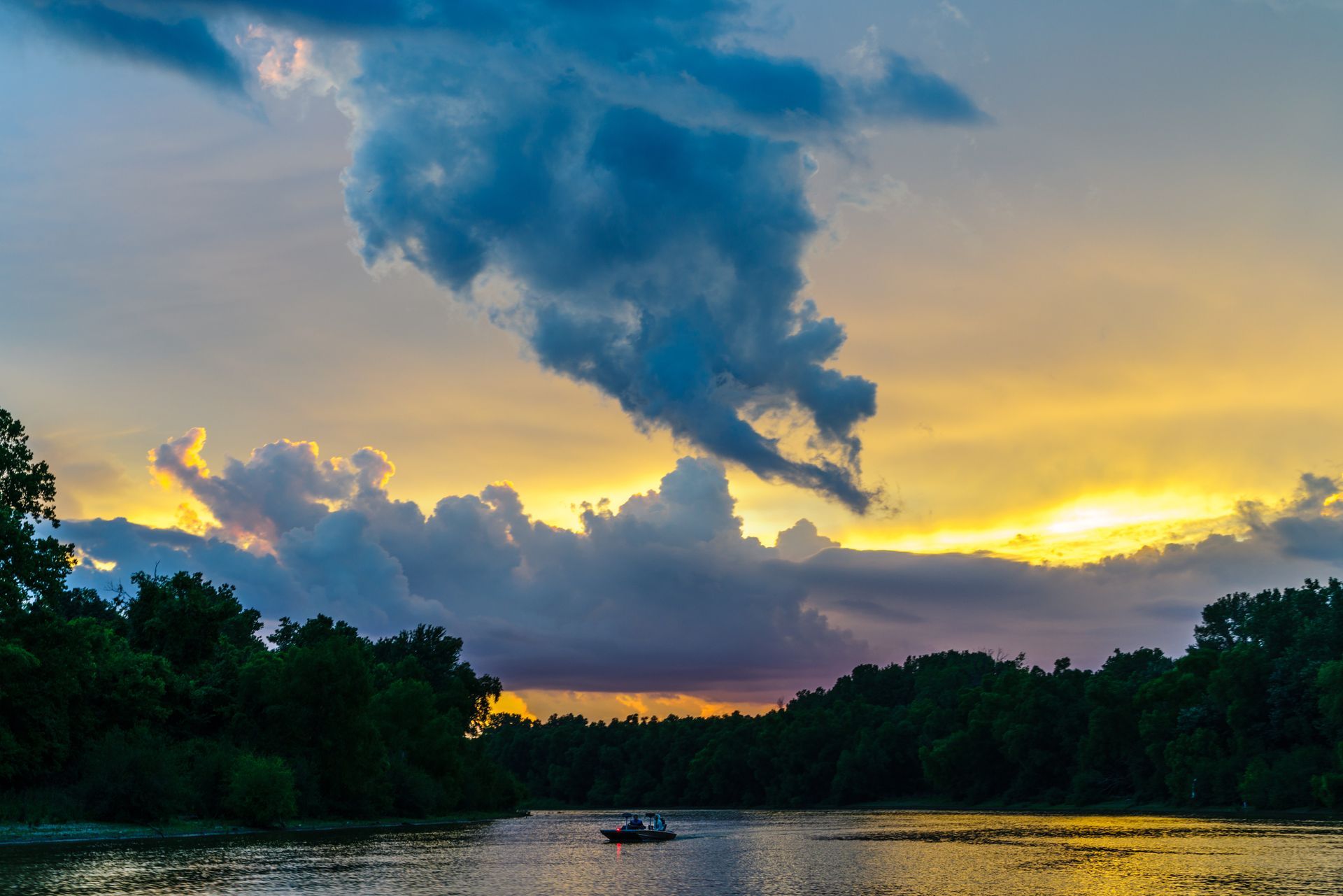 A boat is floating on a river at sunset.