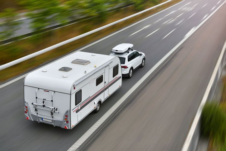 A caravan is being towed by a car on a highway.