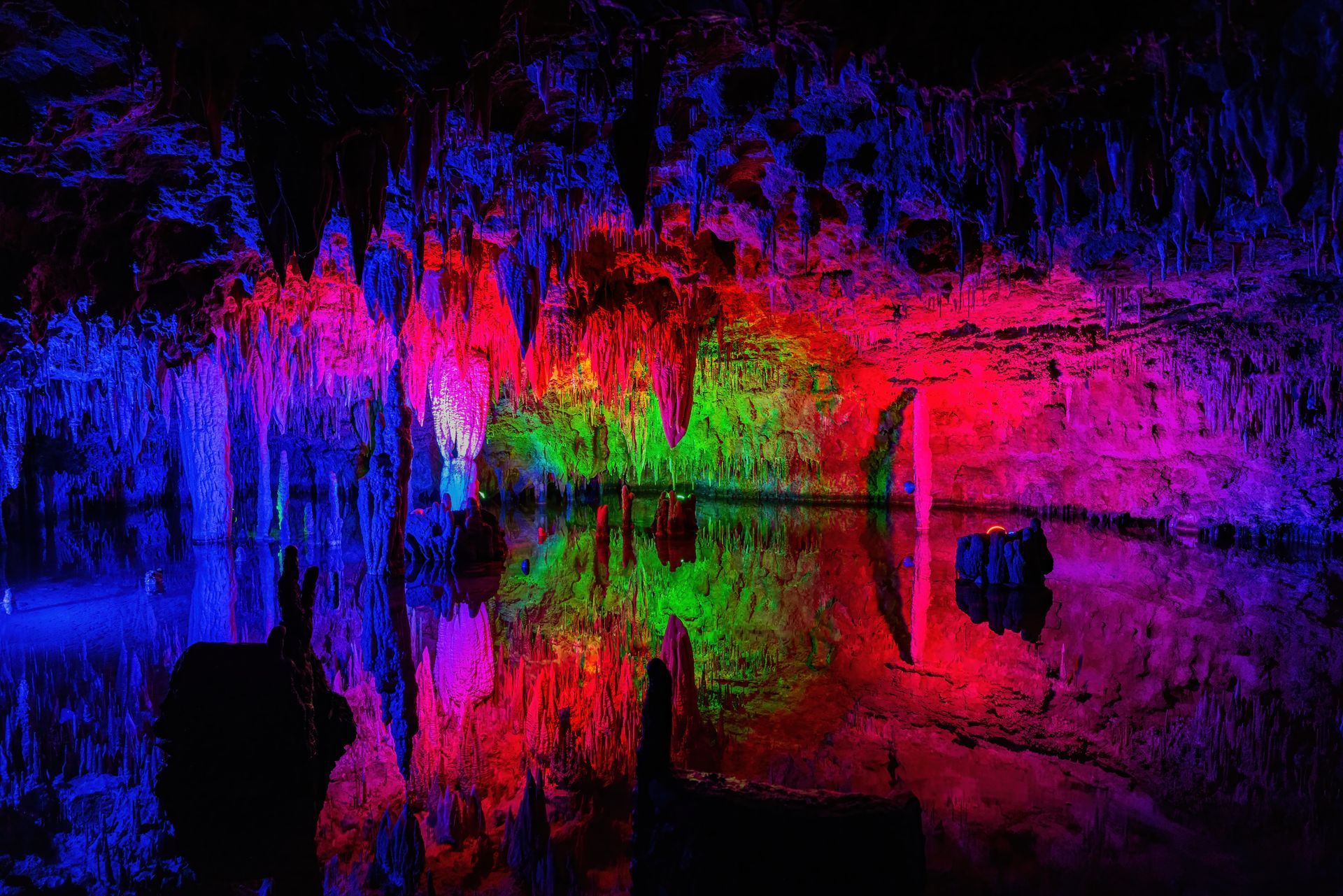 A cave filled with colorful lights and a body of water.