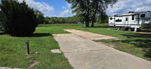 A rv is parked in a grassy field next to a path.