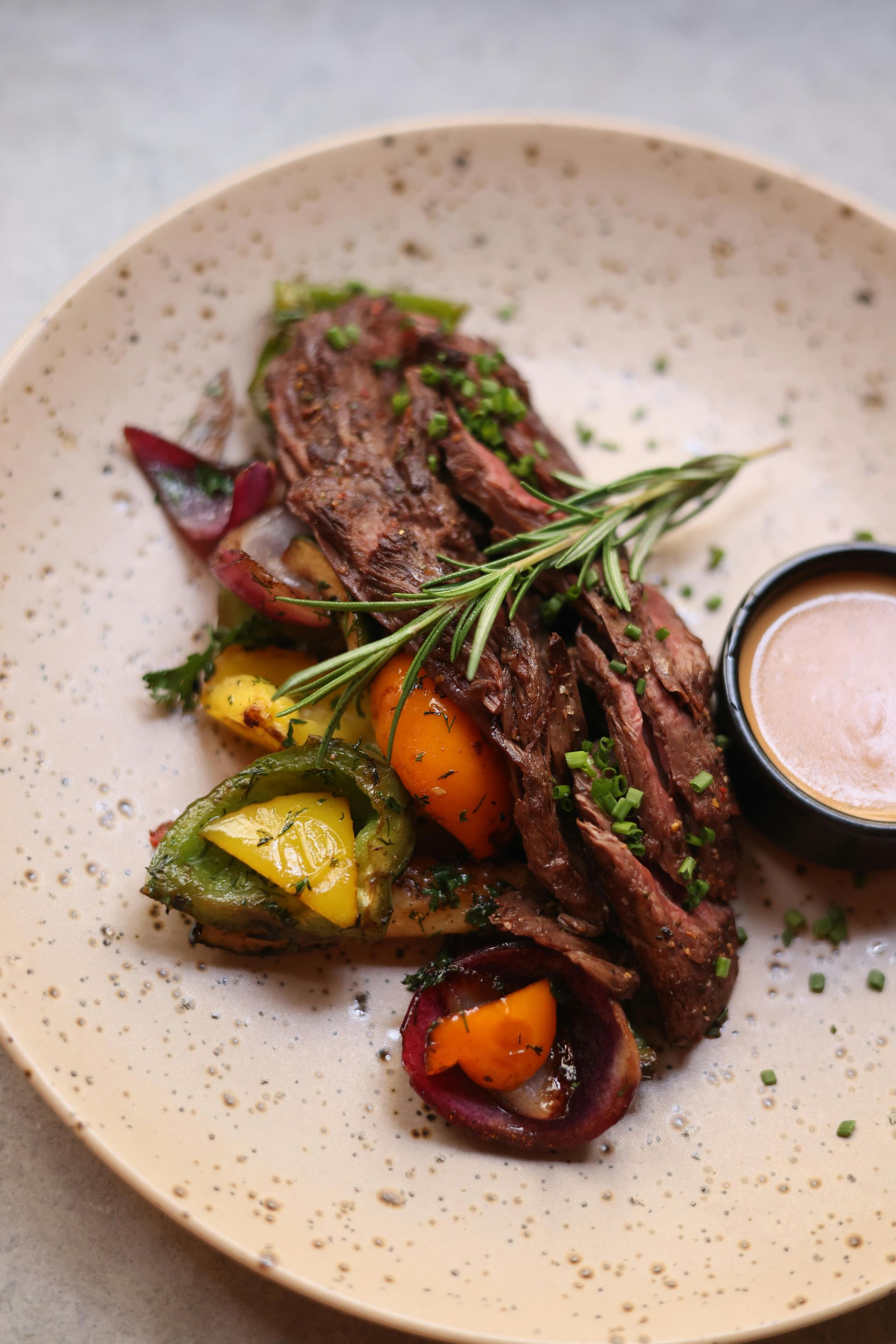 A close up of a plate of food with meat and vegetables on a table.