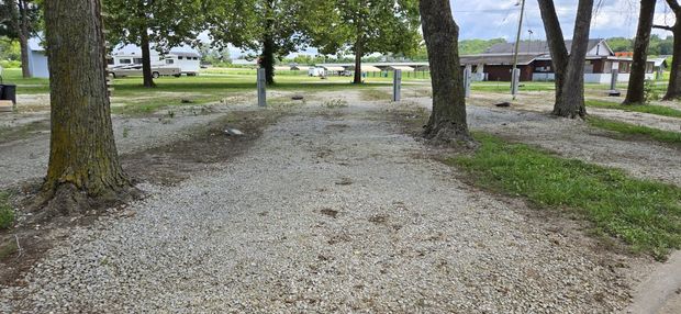 A gravel rv site surrounded by trees in a park.