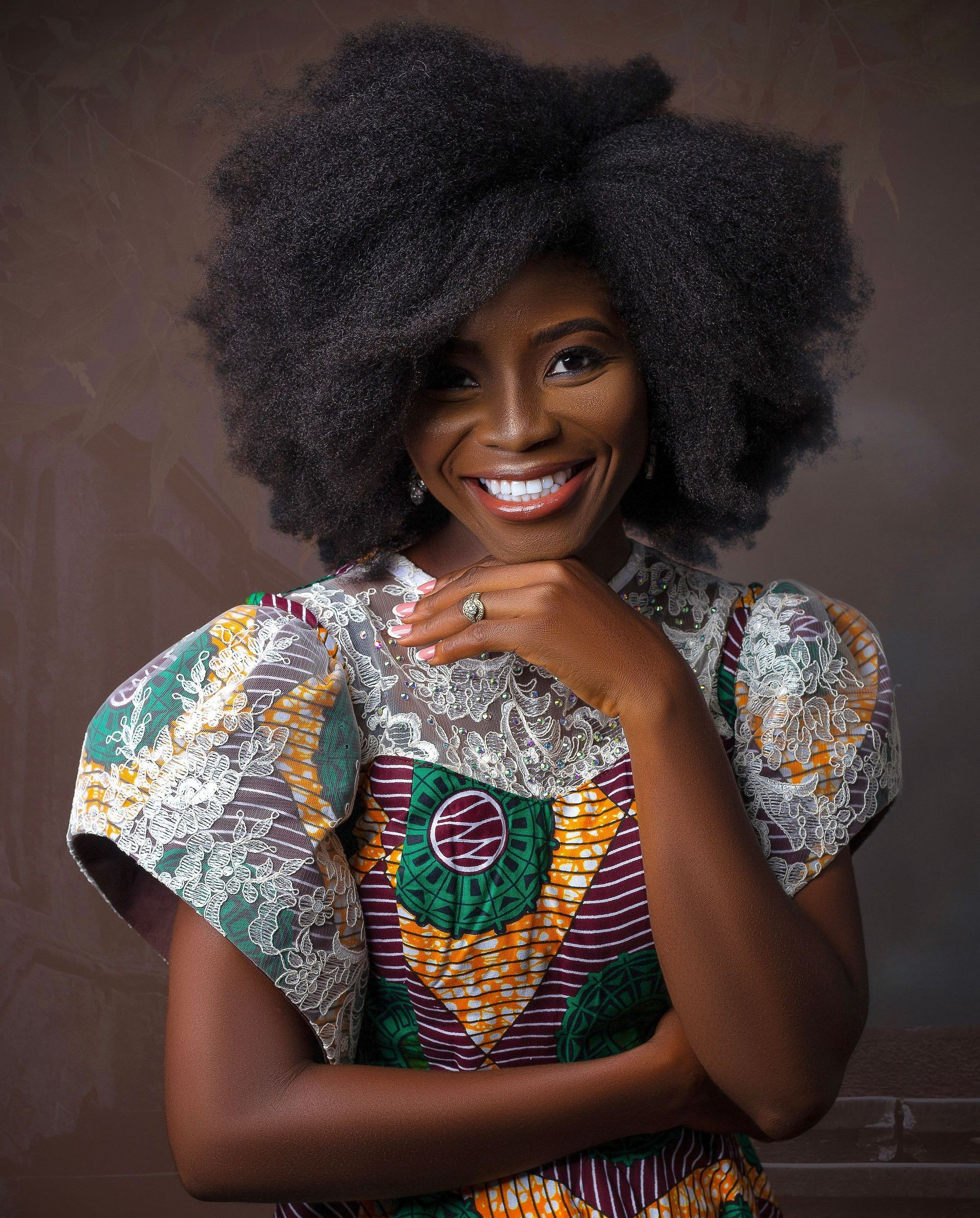 A woman with afro hair and freckles is smiling for the camera.