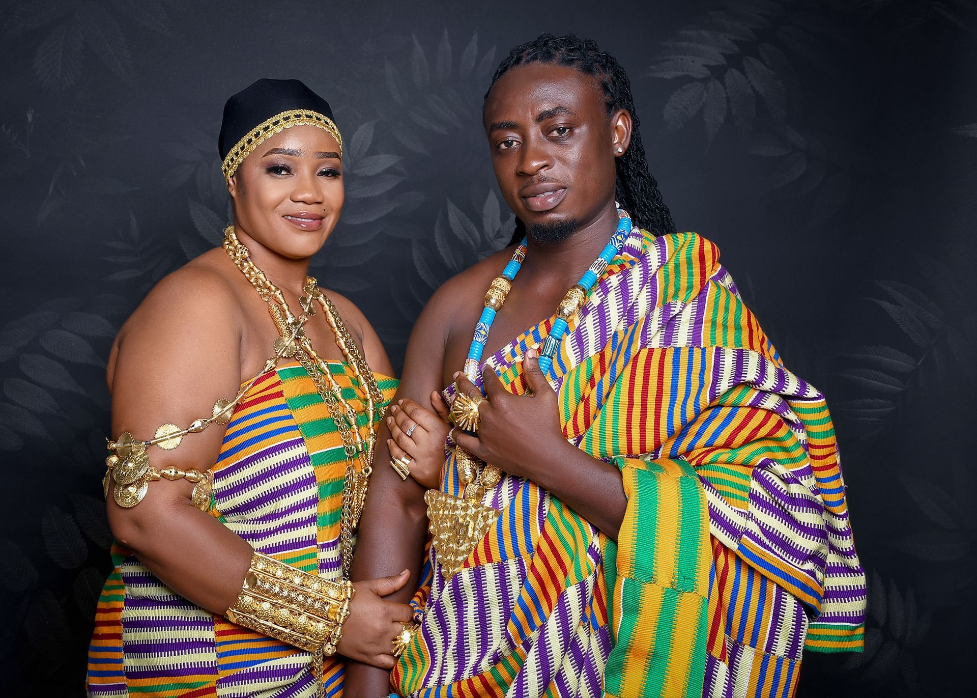 A man and a woman in traditional african clothing are posing for a picture.