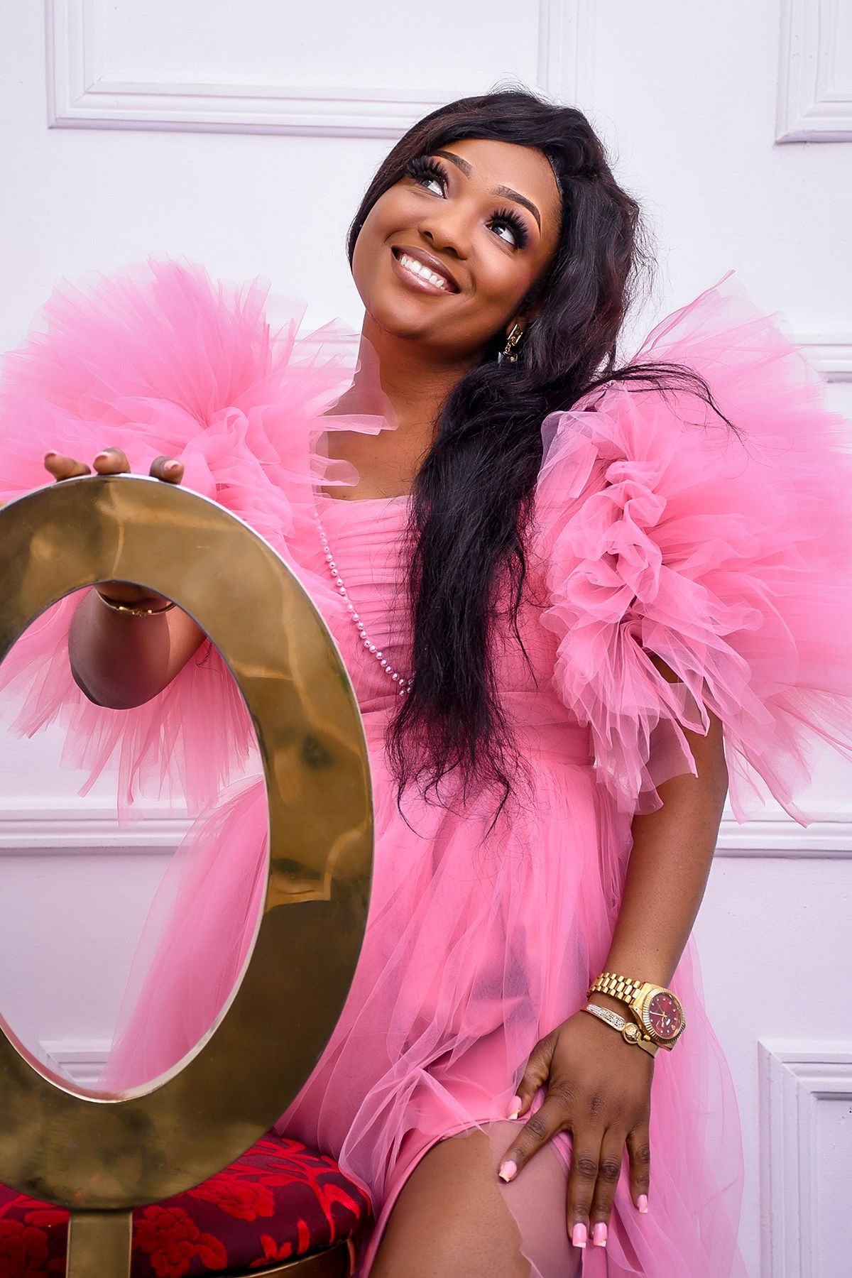 A woman in a pink dress is holding a gold ring.