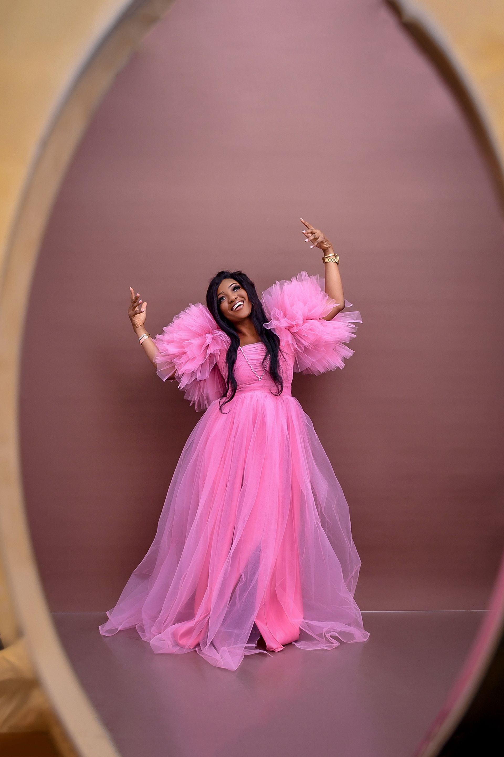 A woman in a pink dress is standing in front of a mirror.