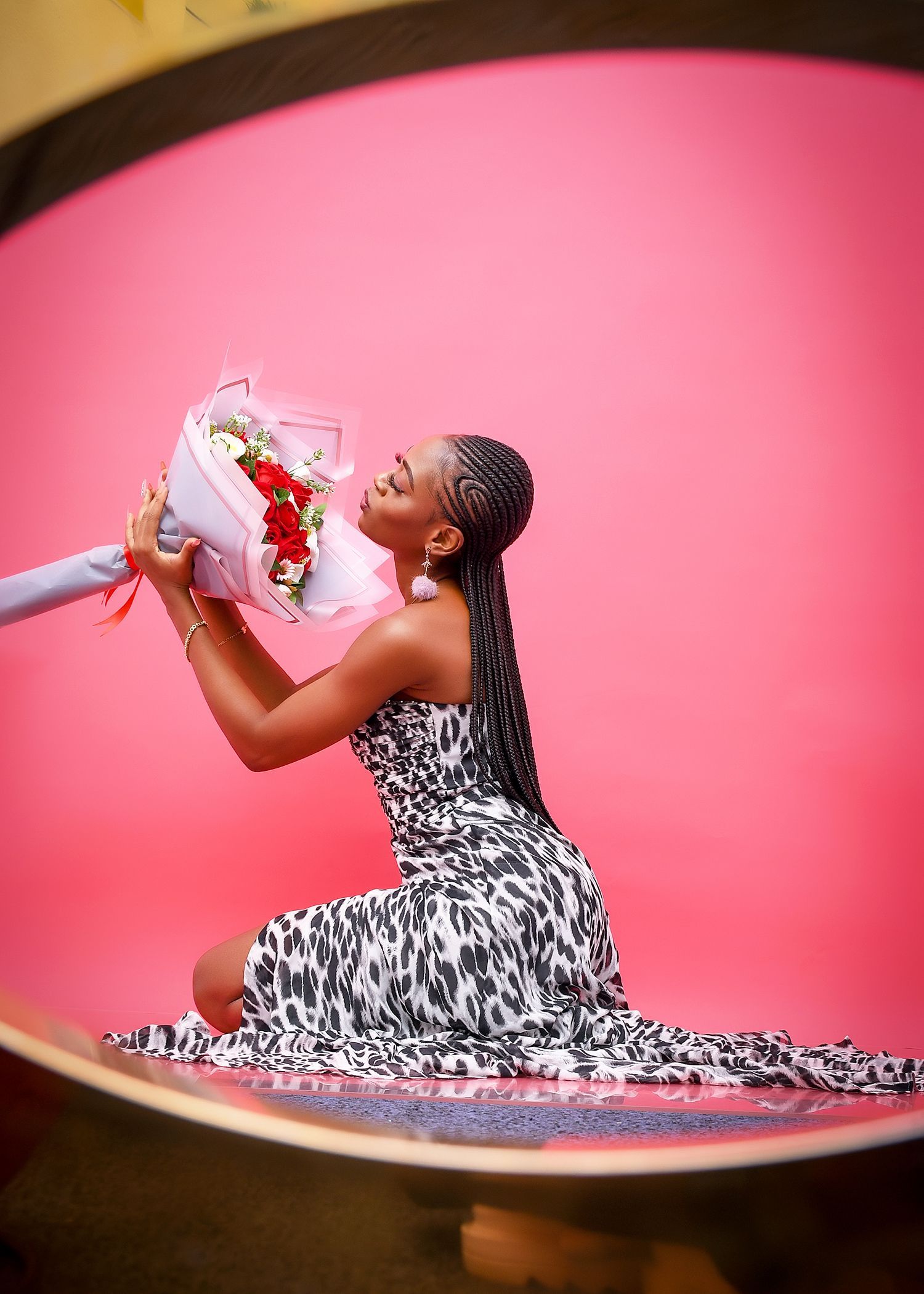 A woman in a black and white dress is kneeling down holding a bouquet of flowers.