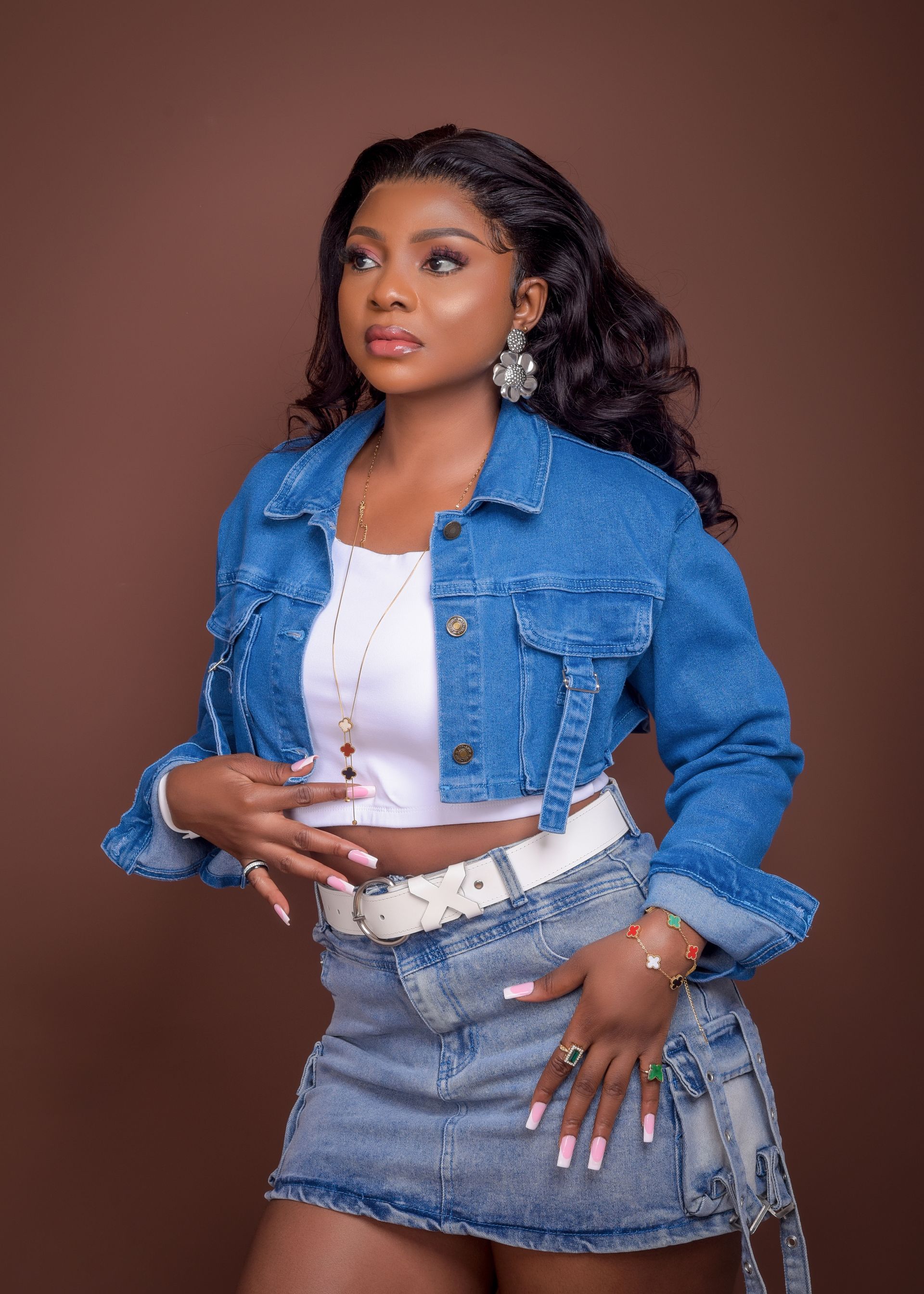 A woman is wearing a denim jacket and a denim skirt.