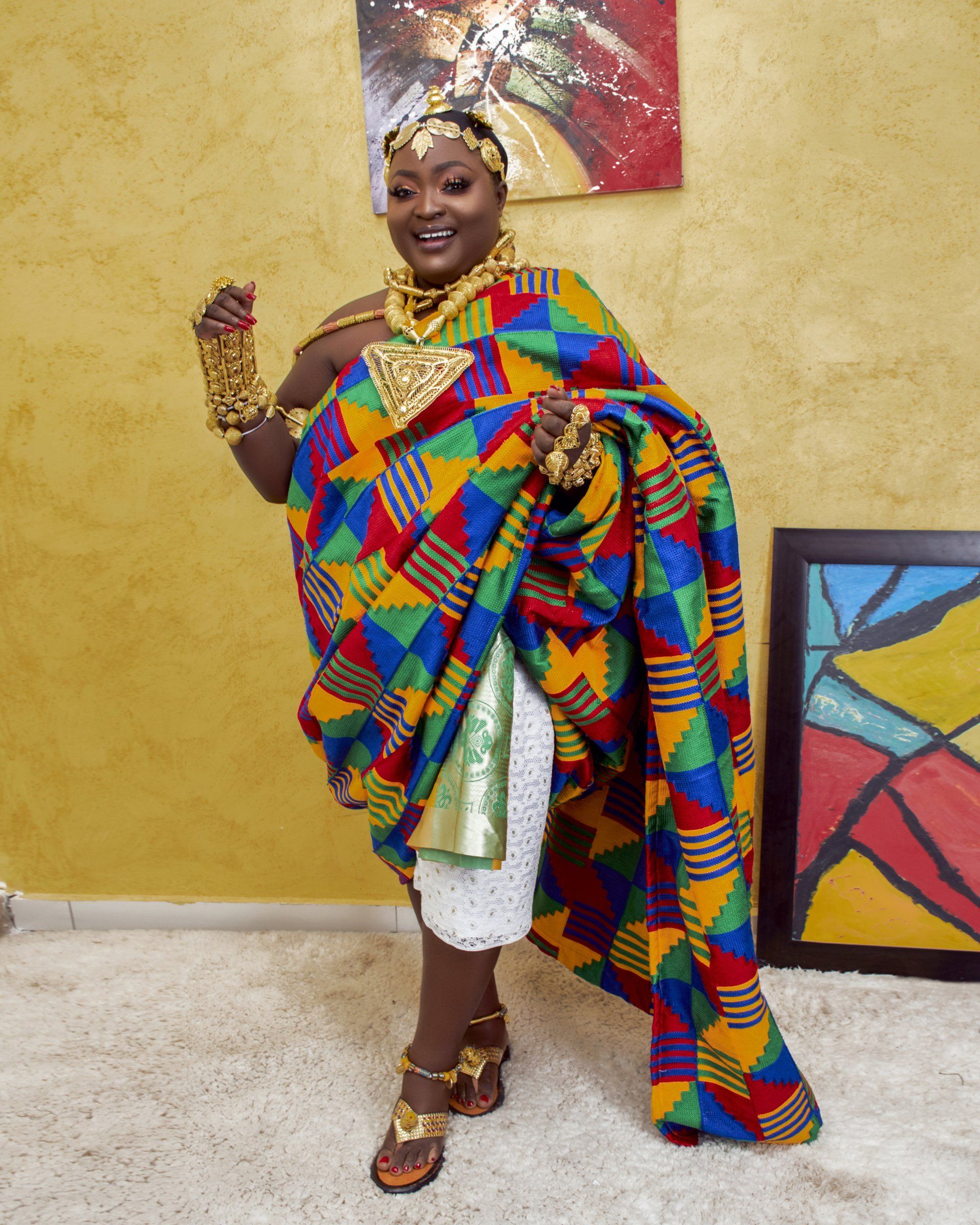 A woman in a colorful dress is standing in front of a painting.