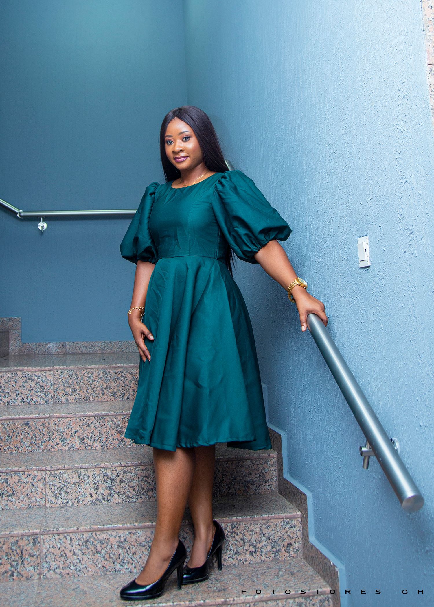 A woman in a green dress is standing on a set of stairs.