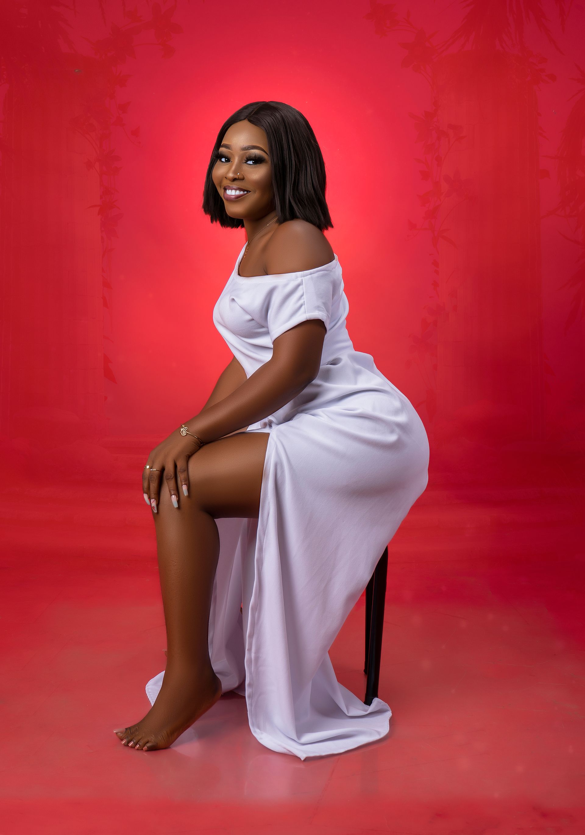 A woman in a white dress is sitting on a chair.