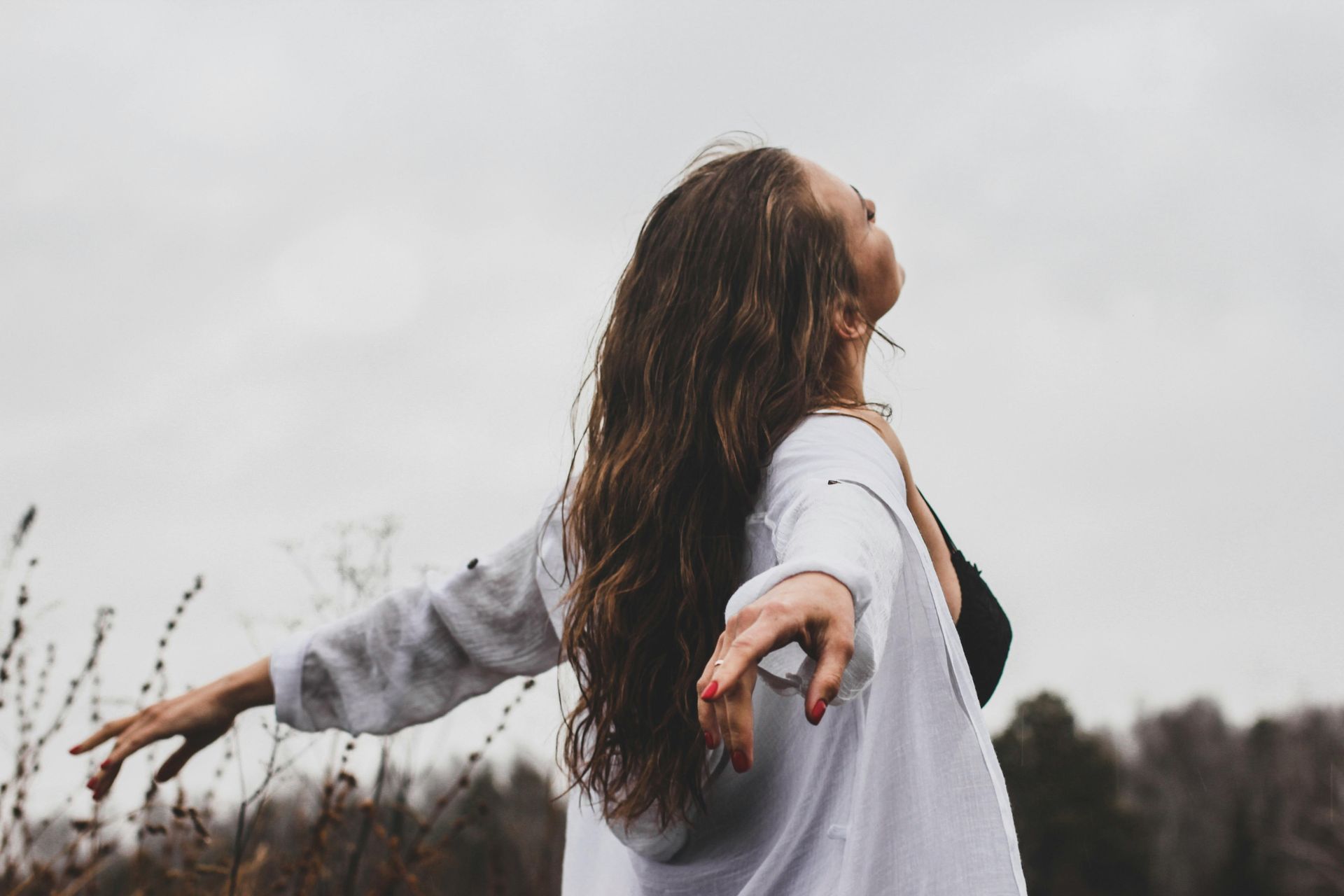 Woman in chest and heart open, extending arms in freedom pose.
