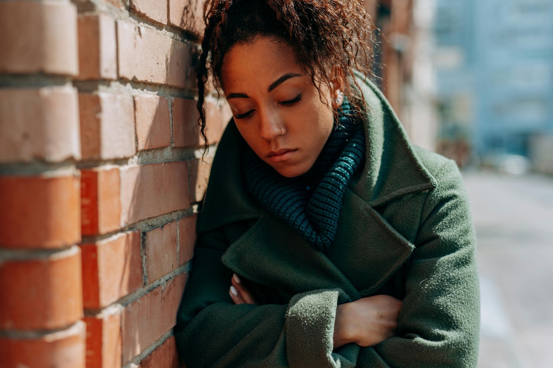 Woman leaning against a wall with arms crossed and loos disappointed.
